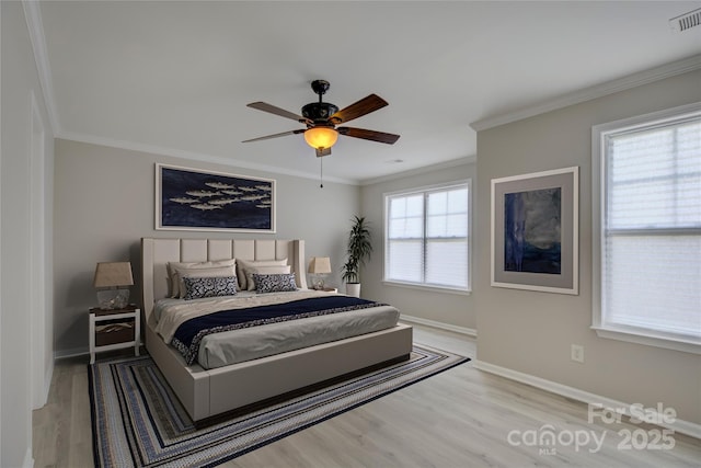 bedroom with light wood finished floors, visible vents, baseboards, a ceiling fan, and crown molding