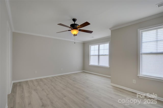 empty room featuring light wood finished floors, visible vents, baseboards, and crown molding