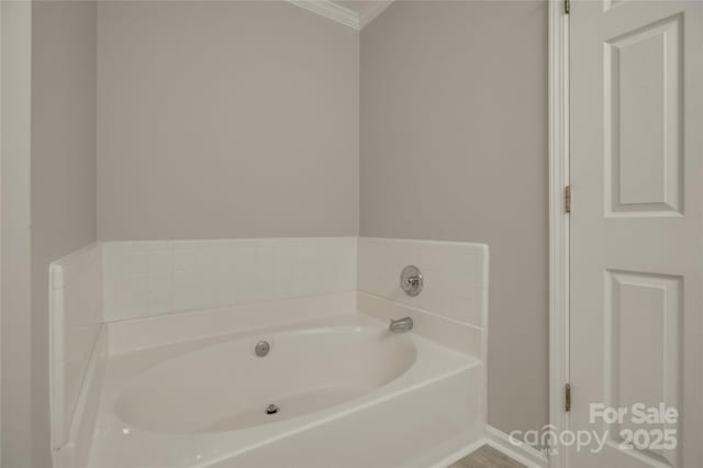 bathroom with ornamental molding and a garden tub