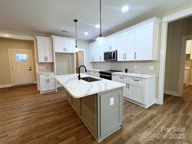 kitchen with an island with sink, light stone counters, black electric range, sink, and white cabinetry