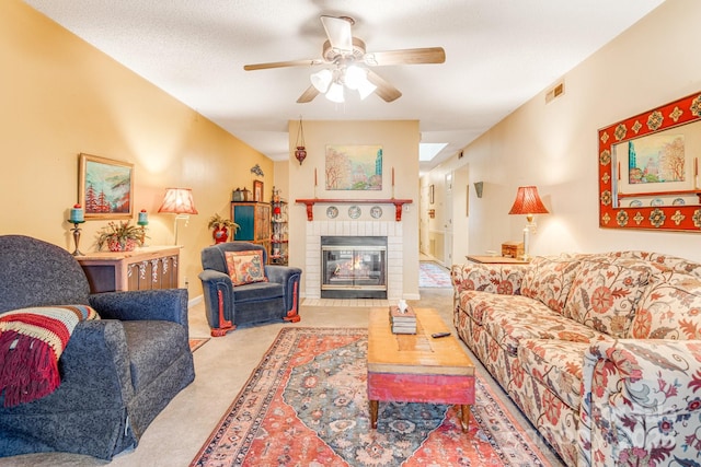 living room with a textured ceiling, a brick fireplace, light colored carpet, and ceiling fan