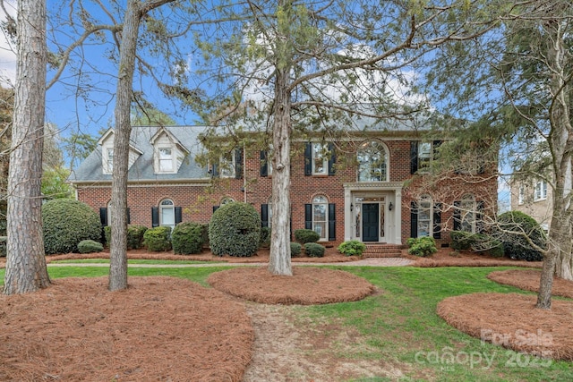 colonial home featuring a front yard and brick siding