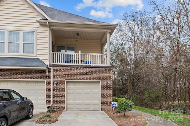 view of front facade featuring a garage, concrete driveway, brick siding, and a balcony