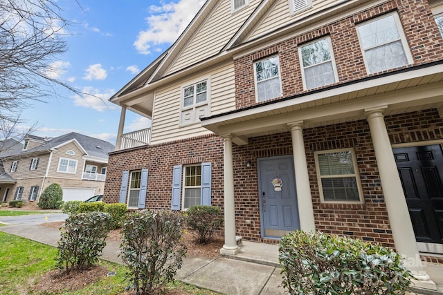 view of exterior entry featuring covered porch and brick siding