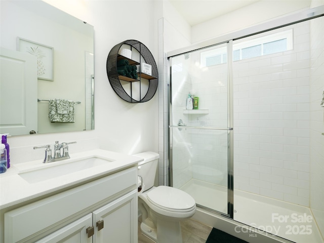 bathroom featuring toilet, a shower stall, and vanity