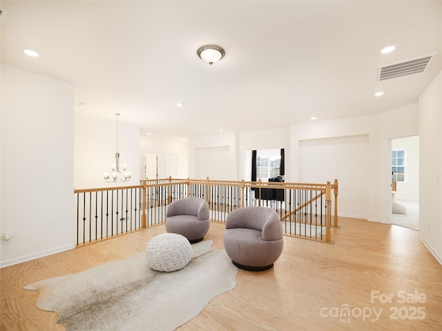 sitting room with recessed lighting, an upstairs landing, visible vents, light wood-style floors, and an inviting chandelier