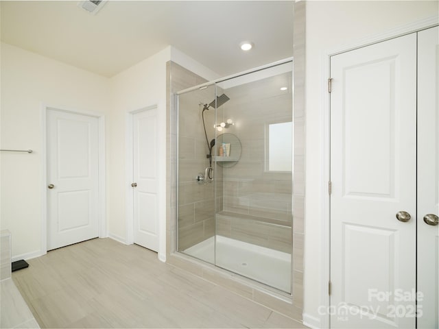 bathroom with a shower stall, visible vents, and baseboards