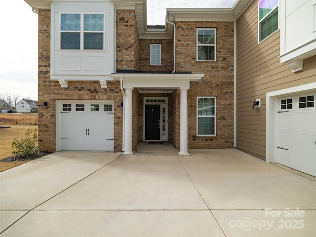 doorway to property featuring concrete driveway, brick siding, and an attached garage