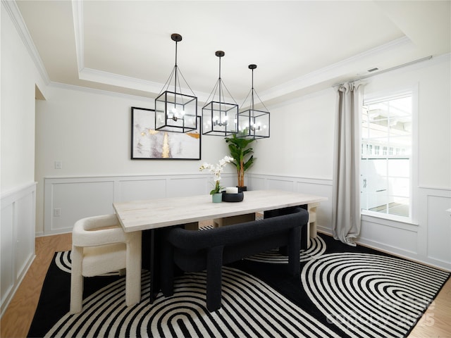 dining area featuring a wainscoted wall, ornamental molding, breakfast area, and wood finished floors