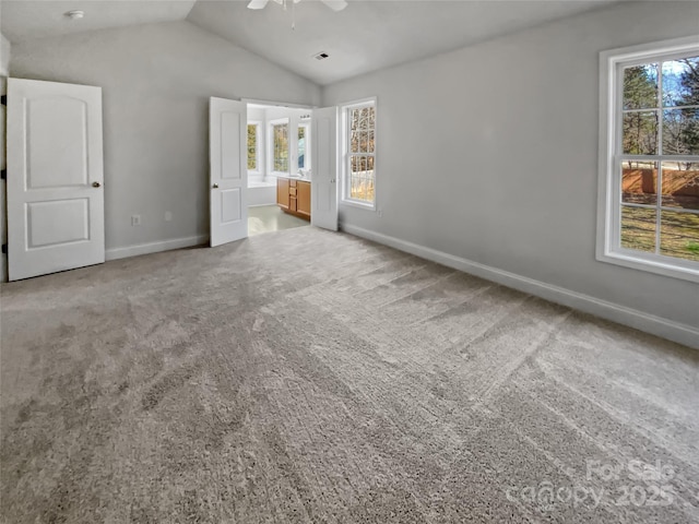 unfurnished bedroom featuring lofted ceiling, multiple windows, and light carpet