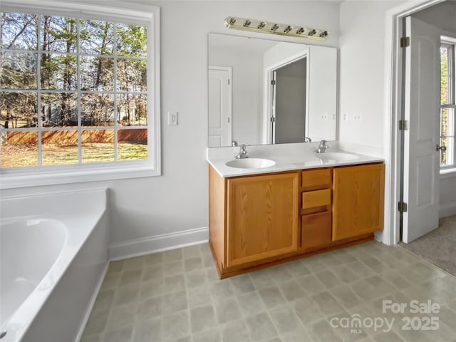 full bath with double vanity, a sink, and a wealth of natural light