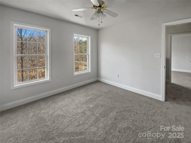 unfurnished room featuring ceiling fan, dark carpet, visible vents, and baseboards