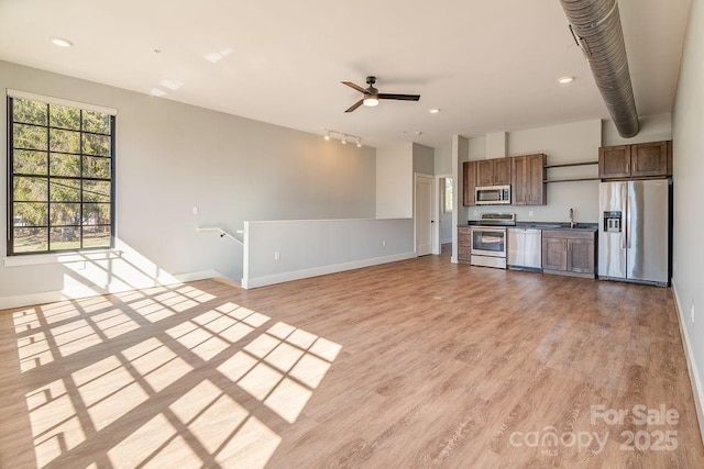 kitchen featuring dark countertops, light wood-style floors, appliances with stainless steel finishes, and open floor plan