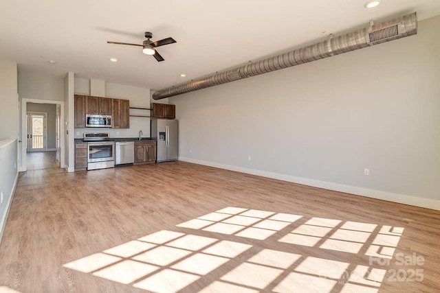 kitchen with baseboards, ceiling fan, stainless steel appliances, light wood-type flooring, and a sink