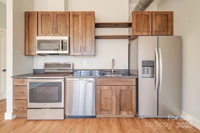 kitchen with brown cabinetry, light wood-style flooring, appliances with stainless steel finishes, open shelves, and a sink