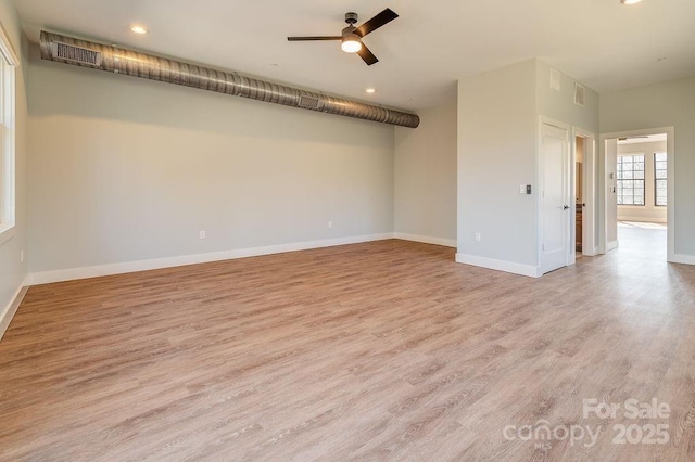 empty room with a ceiling fan, visible vents, light wood-style flooring, and baseboards