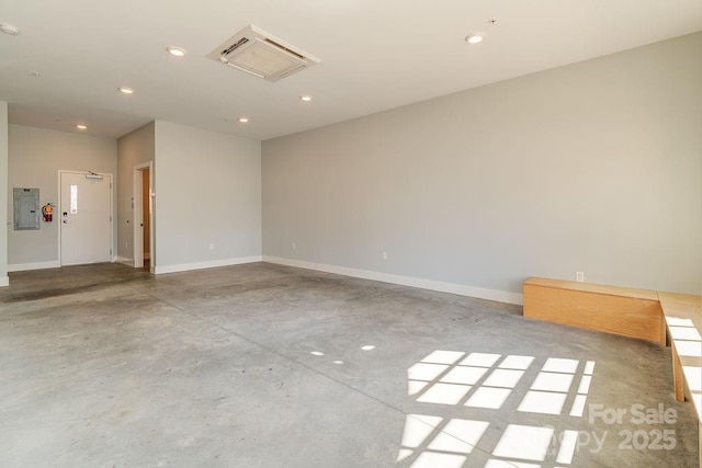 spare room featuring electric panel, baseboards, concrete flooring, and recessed lighting