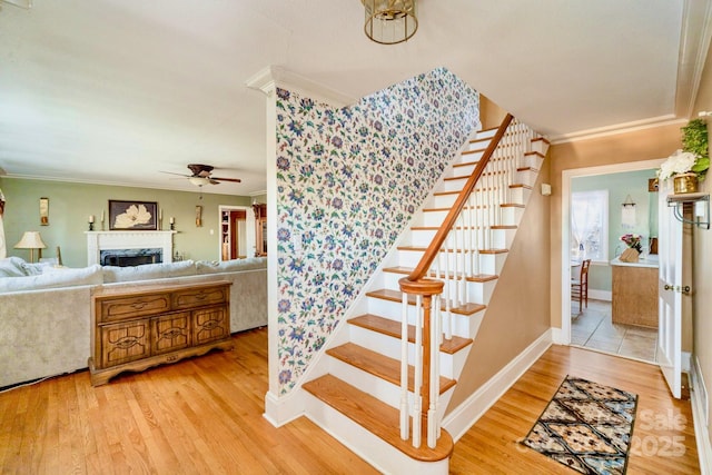 staircase featuring a fireplace, crown molding, and wood finished floors