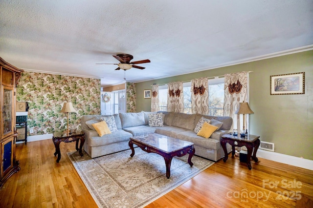 living area featuring a textured ceiling, wood finished floors, visible vents, and baseboards