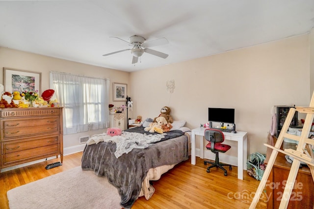 bedroom with ceiling fan, wood finished floors, visible vents, and baseboards