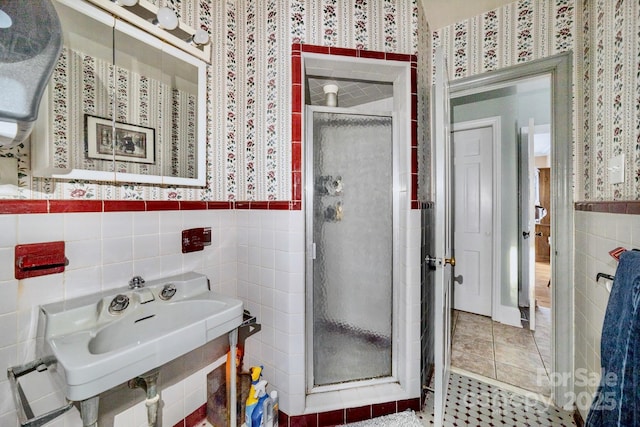 full bath featuring a stall shower, a wainscoted wall, tile walls, and wallpapered walls