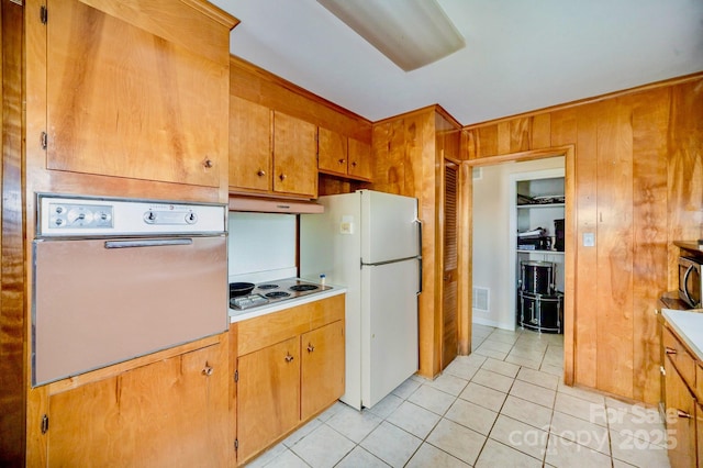 kitchen featuring brown cabinets, stainless steel appliances, light countertops, light tile patterned flooring, and under cabinet range hood