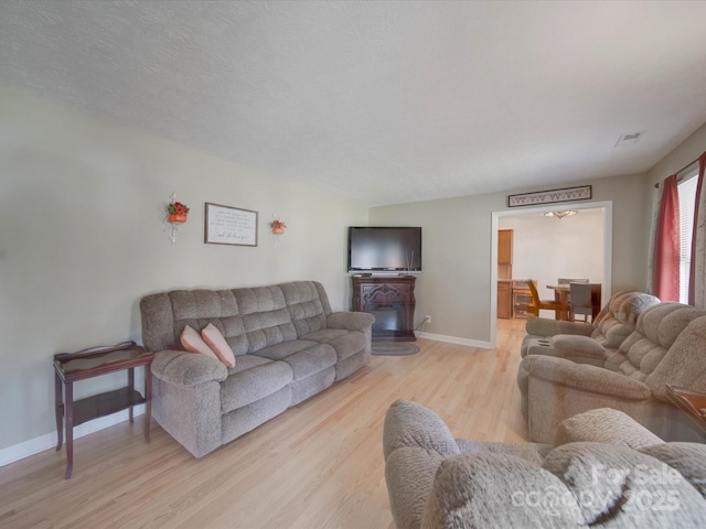 living room with a textured ceiling and light wood-type flooring