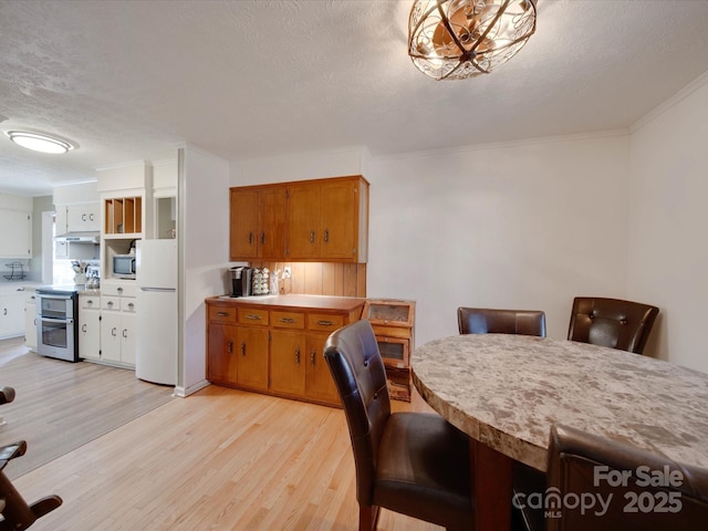 dining area featuring a textured ceiling, light wood-type flooring, and ornamental molding