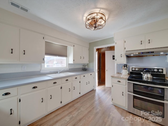 kitchen featuring white cabinets, double oven range, light wood-type flooring, a textured ceiling, and sink