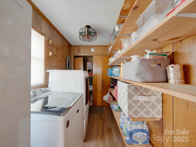 kitchen featuring wood walls, crown molding, washing machine and clothes dryer, and dark hardwood / wood-style floors