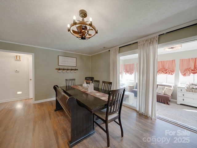 dining area featuring ornamental molding, an inviting chandelier, hardwood / wood-style flooring, and a textured ceiling