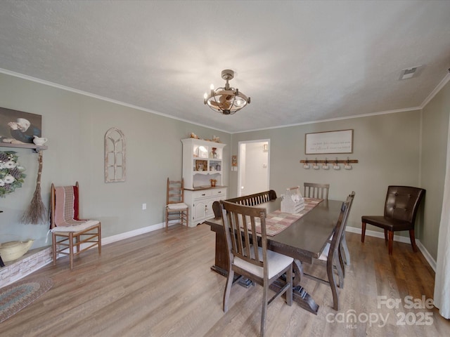 dining area featuring a notable chandelier, light hardwood / wood-style floors, and ornamental molding