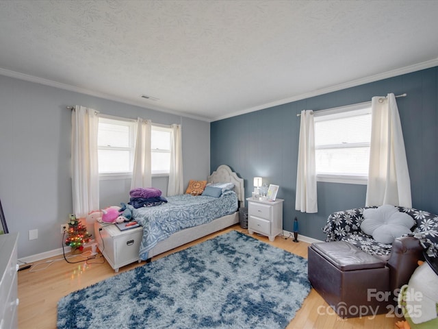 bedroom with multiple windows, a textured ceiling, light hardwood / wood-style floors, and ornamental molding