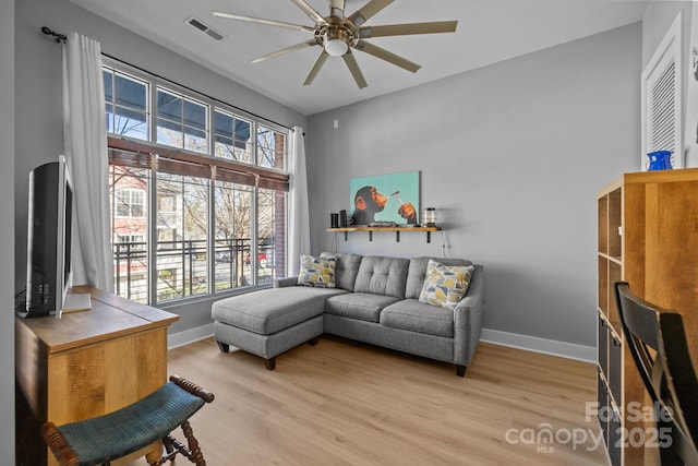 living room with light wood finished floors, baseboards, visible vents, and a ceiling fan