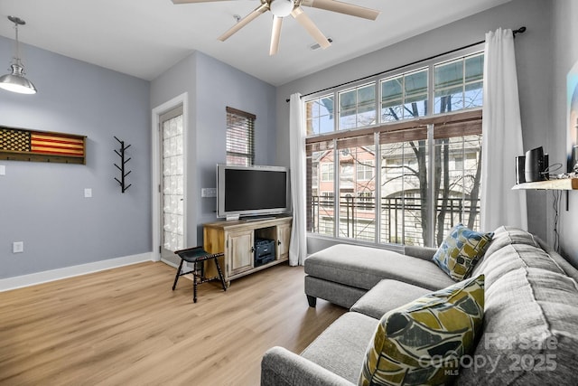 living room featuring light wood-style floors, ceiling fan, and baseboards