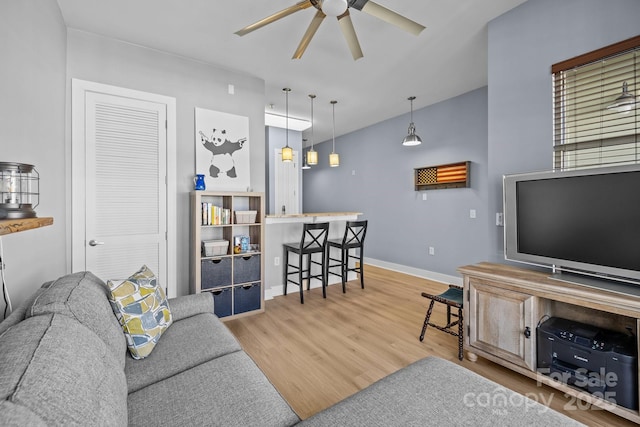 living area with baseboards, a ceiling fan, and wood finished floors