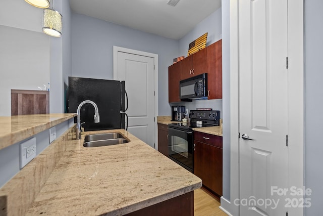 kitchen featuring decorative light fixtures, visible vents, light wood-style flooring, a sink, and black appliances