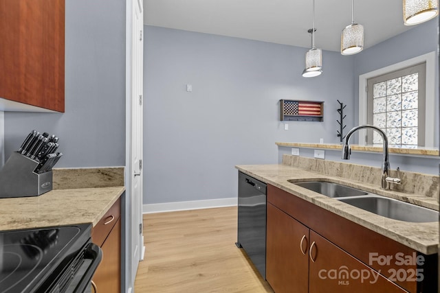 kitchen featuring black dishwasher, light wood finished floors, hanging light fixtures, a sink, and baseboards