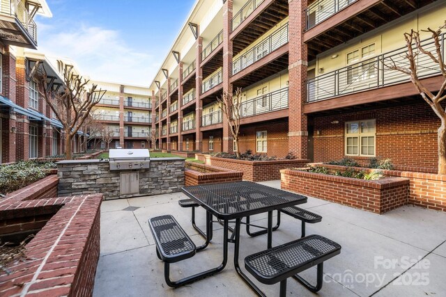 view of patio featuring exterior kitchen, outdoor dining area, and a grill