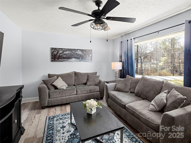 living room featuring a textured ceiling, ceiling fan, and light hardwood / wood-style flooring