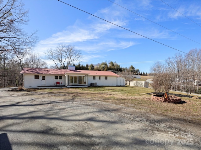 single story home with central AC unit and a fire pit