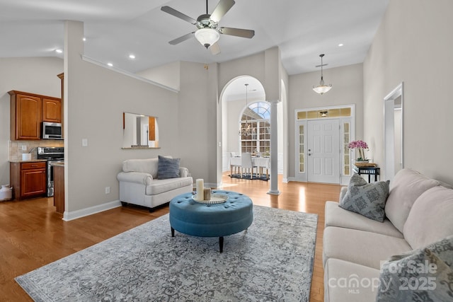 living area featuring high vaulted ceiling, light wood-type flooring, and baseboards