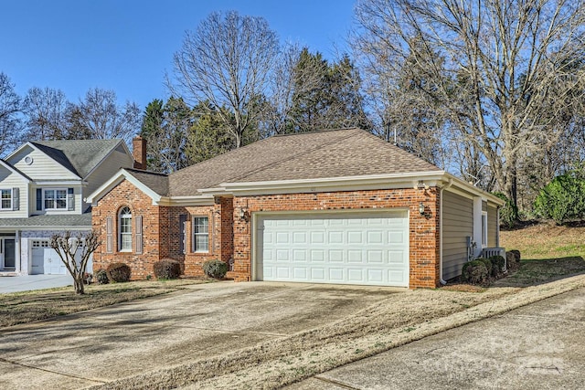 traditional-style house with a garage, roof with shingles, concrete driveway, and brick siding