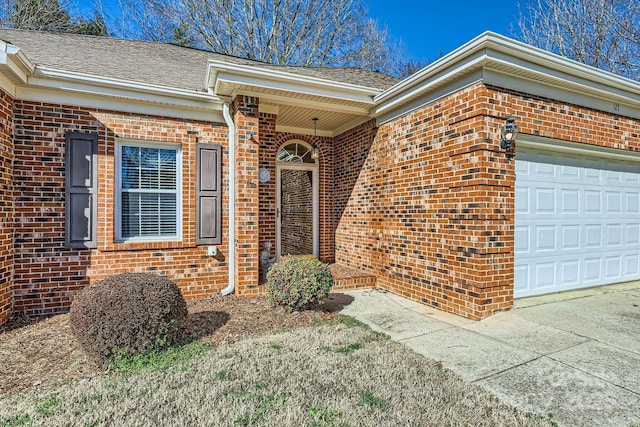 doorway to property featuring a garage, roof with shingles, and brick siding