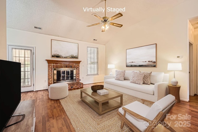 127 Lakewood Circle Dr, Mooresville, NC 28117 - living room featuring lofted ceiling, a textured ceiling, a fireplace, wood finished floors, and visible vents