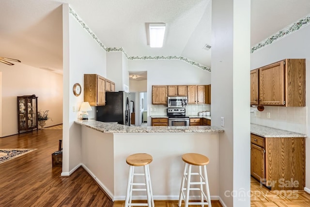 127 Lakewood Circle Dr, Mooresville, NC 28117 - kitchen with visible vents, brown cabinets, wood finished floors, vaulted ceiling, and stainless steel appliances