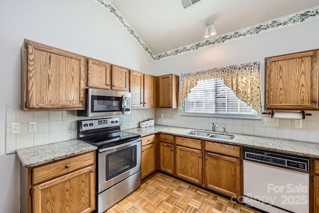 127 Lakewood Circle Dr, Mooresville, NC 28117 - kitchen featuring visible vents, brown cabinetry, lofted ceiling, appliances with stainless steel finishes, and a sink