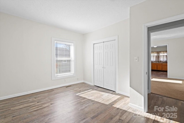 unfurnished bedroom featuring a closet, wood-type flooring, and a textured ceiling