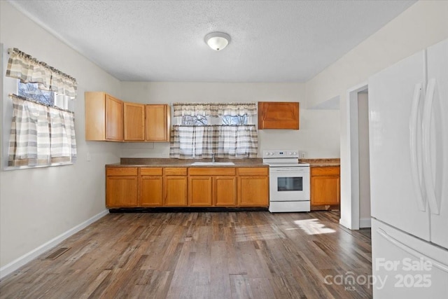 kitchen featuring white appliances, a wealth of natural light, wood-type flooring, and a textured ceiling