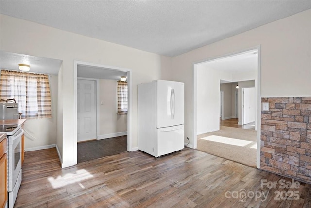 interior space featuring white appliances, wood-type flooring, and a textured ceiling